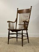 A late 19th / early 20th century oak spindle back open armchair, with saddle seat, raised on