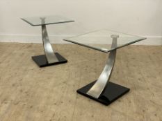 A pair of square glass topped occasional tables raised on polished steel arched support and black