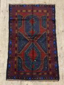 A hand knotted baluchi rug, the red field with geometric design and bordered 140cm x 83cm