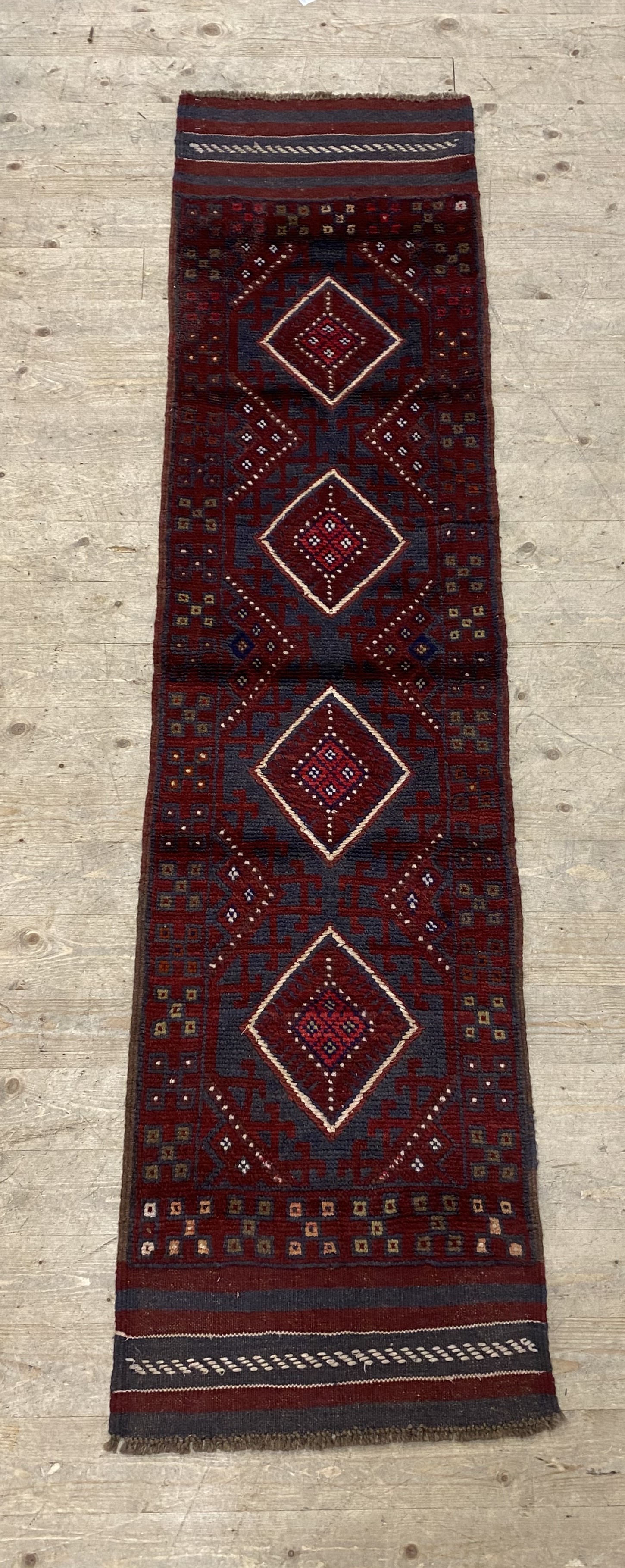 A red ground Meshwani runner rug 230cm x 57cm