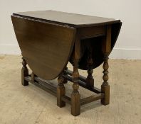 An oak gateleg drop leaf dining table, the oval top with two drop leaves raised on turned and