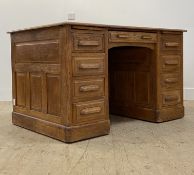An early 20th century oak desk, the panelled top over two slides, one long and eight short