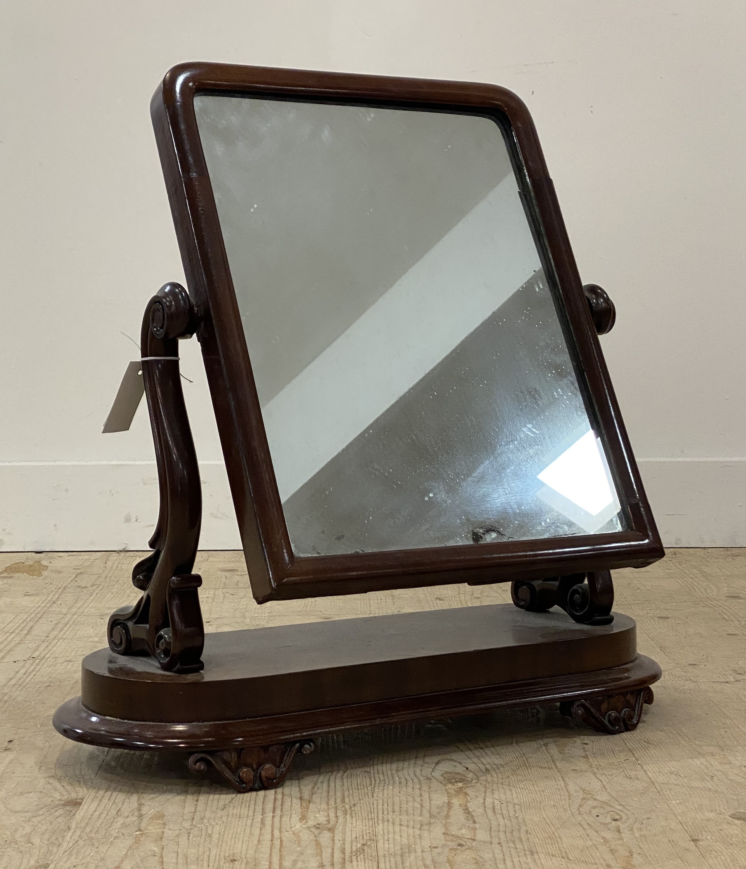 A Victorian mahogany toilet mirror, the rectangular mirror swivelling between two scrolled uprights,