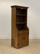 An early 20th century oak side cabinet, with top open shelves above two panelled cupboard doors,