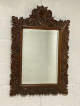 A late 19th century Bavarian/Black Forest wall hanging mirror, the oak frame carved with green man