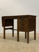A 1930's / 40's oak desk, the top with drop leaf to one end and three drawers opposing, raised on
