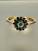 A 18ct gold diamond and emerald cluster ring, the central circular brilliant cut diamond in claw set