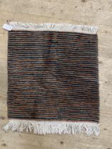 A small wool rug of lineal design with tassels to each end 79cm  65cm.