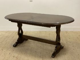 An oak extending dining table, the oval top with magic leaf to centre raised on panel end supports