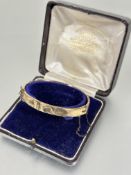 A Edwardian 9ct gold buckle style stiff hinged hollow engraved bracelet a/f with original fitted