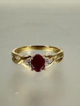 A 9ct gold ruby and diamond ring set oval ruby approximately 0.02ct in four claw setting flanked