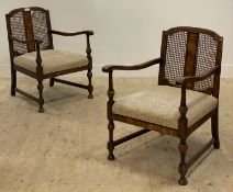 A pair of 1930's walnut open armchairs, each with a bergere panelled back above a drop in