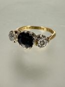 A 8ct gold and platinum set three stone sapphire and diamond ring, the circular sapphire