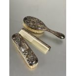 A vintage three piece plated three piece dressing table brush set to include plastic toothed comb,