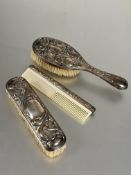 A vintage three piece plated three piece dressing table brush set to include plastic toothed comb,