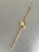 A ladys 9ct gold Baume vintage wristwatch with gilt dial on 9ct gold twin chain style strap and