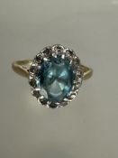 A 18ct gold and platinum ring set oval blue zircon within a surround of fourteen diamond points,
