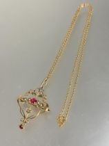 An Edwardian yellow metal open work scrolling pendant brooch set two pink gem stones with seed pearl