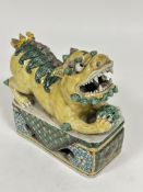 A 19thc Chinese porcelain crouching Shi cub with pierced ball between its feet mounted on