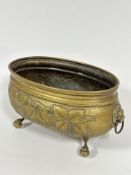 A Edwardian chased oval brass planter with leaf and flower head side panel designs and cast lion