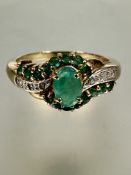 A 9ct gold ring set oval central emerald within a diamond miligrain and emerald set borders, P  2.