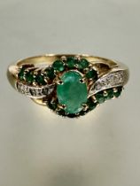 A 9ct gold ring set oval central emerald within a diamond miligrain and emerald set borders, P  2.