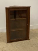 An early 20th century stripped walnut wall hanging corner cabinet with single glazed door