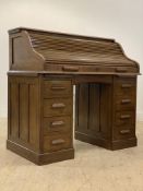 An early 20th century oak roll top desk, the serpentine tambour top opening to a fitted interior,