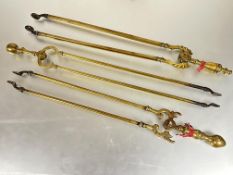 A group of three Victorian cast brass fire tongs, two with pommel handles and the other with urn