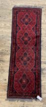 A Turkish wool runner rug, the red ground with four medallions and bordered 163cm x 52cm.