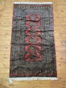 H hand knotted Turkmen bokhara rug, the field with geometric guls within a deep guarded border 175cm