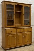 A polished pine dresser, the top section fitted with a open shelf and drawer flanked by two glazed