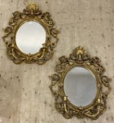 A pair of ornate gilt composition framed Girandole wall mirrors in the Rococo style, each with an