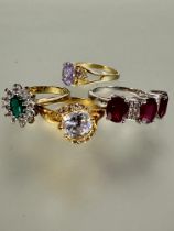 A group of three gilt metal paste set rings and a silver three red stone set ring, N-R (4)