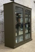 A Late 19th / early 20th century green painted shops display cabinet, the two glazed doors enclosing