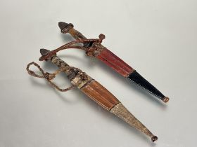 A pair of African steel bladed short daggers with leather and snake / lizard panels and leather