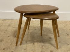 Ercol, a blonde elm 'pebble' nest of two tables, each raised on turned and tapered supports.