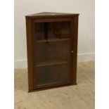 An early 20th century stripped walnut wall hanging corner cabinet with single glazed door