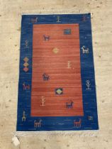 A Gabbeh style flatweave rug, made in India, the red field with stylised animal motif. 170cm x 96cm.
