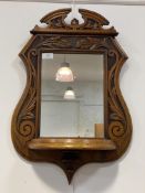 An Arts and Crafts period walnut wall hanging mirror, the frame, of Cartouche outline, carved in low