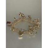 A 9ct gold double kerb link bracelet mounted with eleven various charms including a poodle, heart,