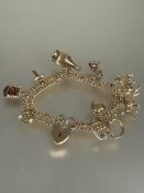 A 9ct gold double kerb link bracelet mounted with eleven various charms including a poodle, heart,