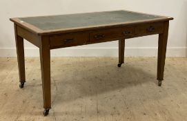 An Edwardian oak writing table, the top inset with green skiver, above three frieze drawers,