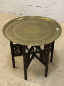 A 19th century eastern brass and carved hardwood tray top table. H57cm, D64cm.