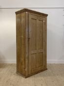 A late 19th century pine kitchen cupboard, the projecting cornice above a panelled door enclosing