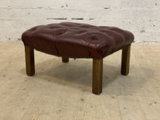 A stained beech framed footstool with deep buttoned oxblood leather upholstered top. H33cm, L60cm.