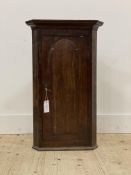 A George III oak wall hanging corner cupboard of small proportions, the projecting cornice above a