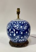 A 20thc Chinese blue and white ceramic table lamp raised on a circular wooden base. (h-35cm w-22cm)
