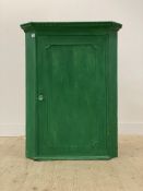 A George III green painted oak wall hanging corner cabinet, the dentil cornice above a panelled door