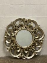A contemporary silvered composition circular wall mirror with 'C' scrolls to frame. D80cm.